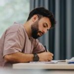 Medizinstudent sitzt an einem Schreibtisch und plant seinen beruflichen Einstieg in die Weiterbildung zur Allgemeinmedizin