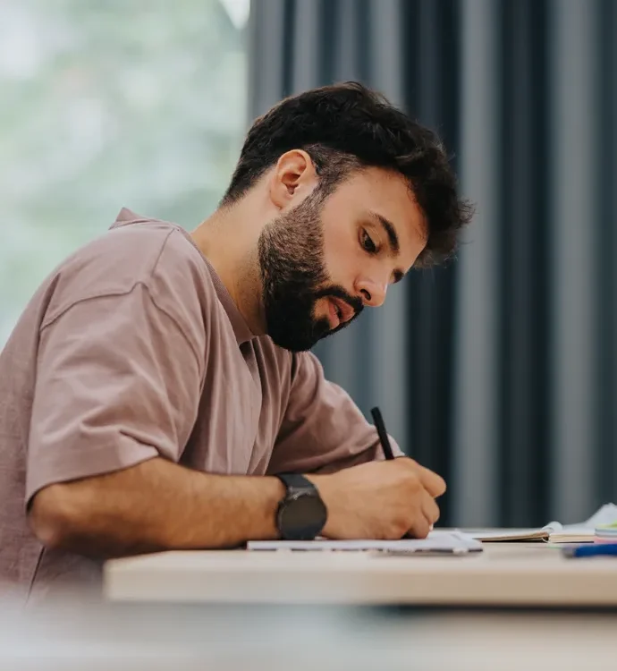 Medizinstudent sitzt an einem Schreibtisch und plant seinen beruflichen Einstieg in die Weiterbildung zur Allgemeinmedizin