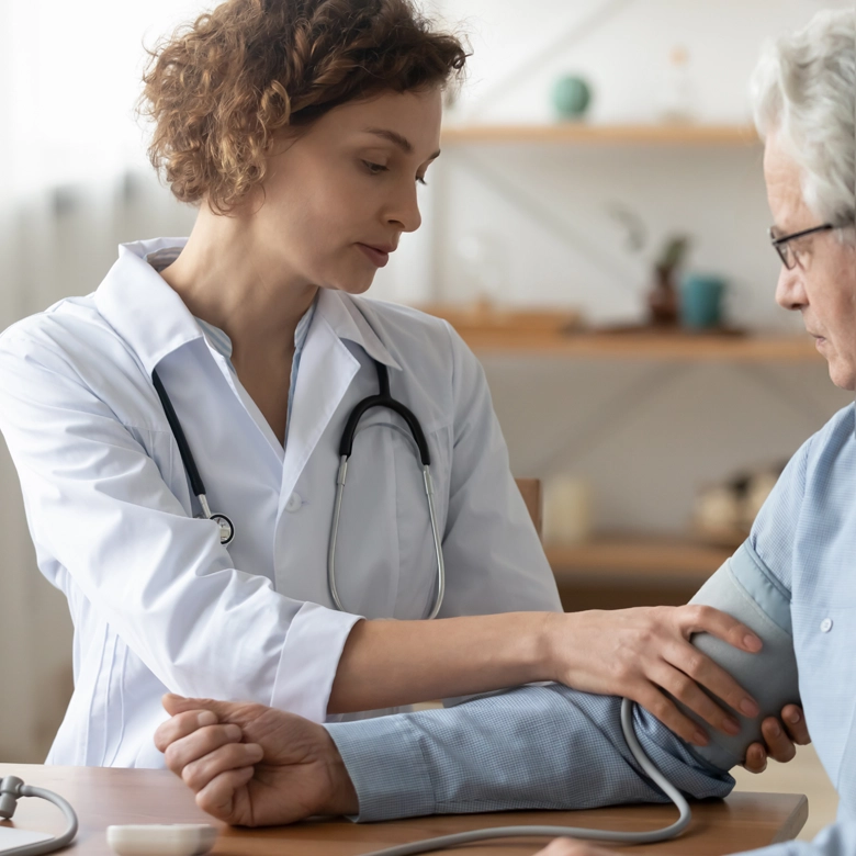 Hausärztin misst den Blutdruck eines älteren Patienten während einer Untersuchung