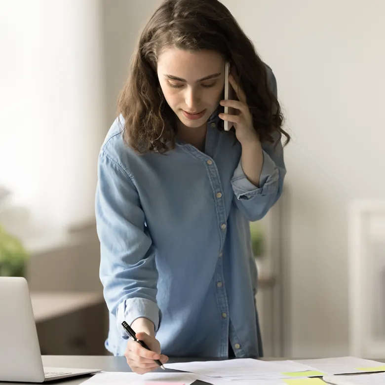 Ärztin telefoniert am Schreibtisch und organisiert ihren Praxisalltag in einem ruhigen und hellen Arbeitszimmer